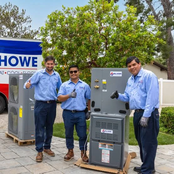 Three HVAC service professionals standing beside heating and cooling equipment